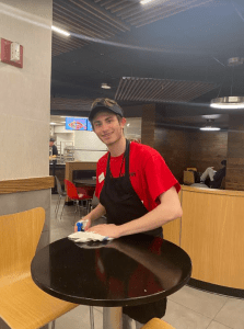 Boy smiling while wiping tables at Sbarro's Pizza