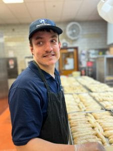 Boy smiling while making garlic bread at Redifer Commons 